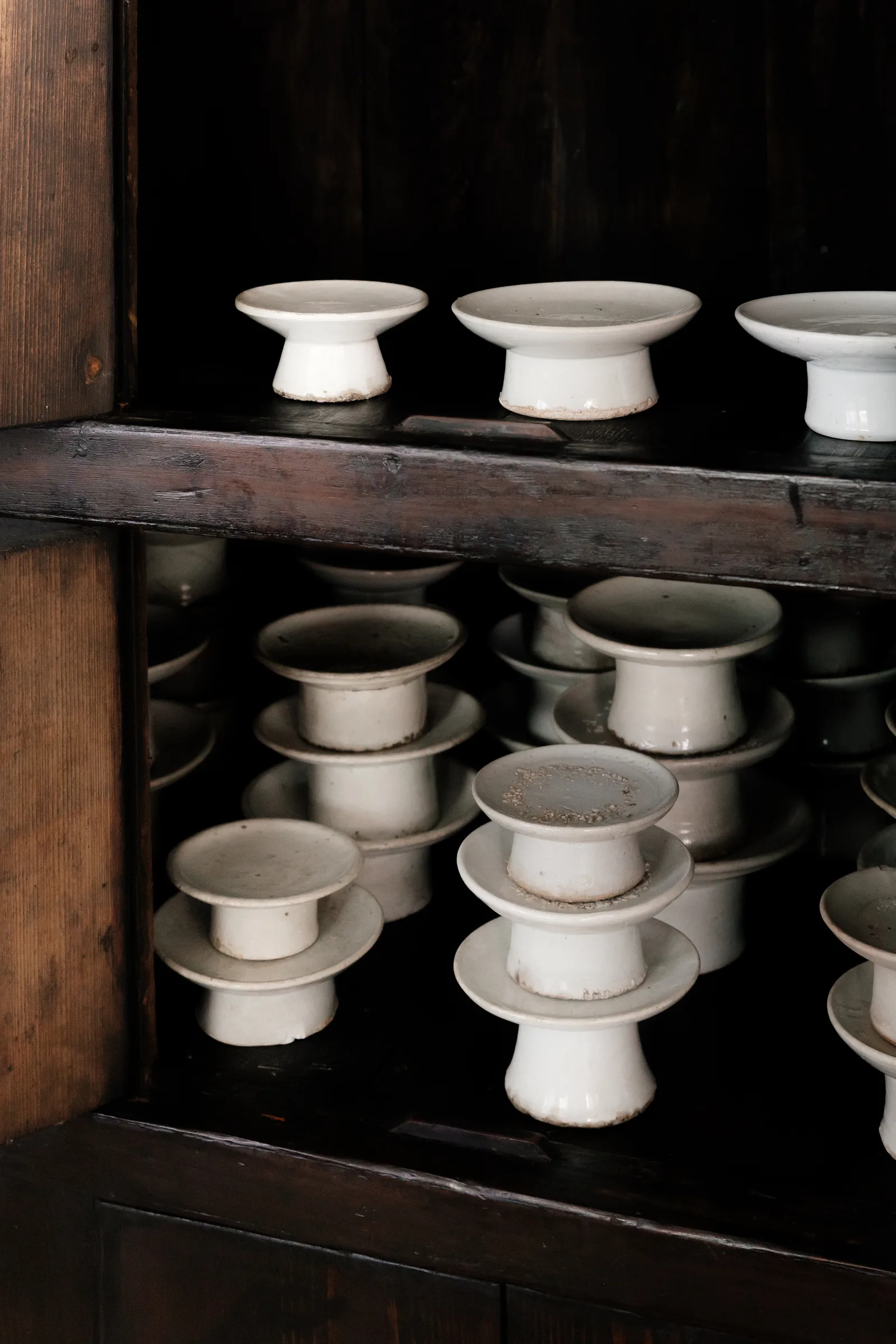 Open shelf cabinet styled with stacked white porcelain