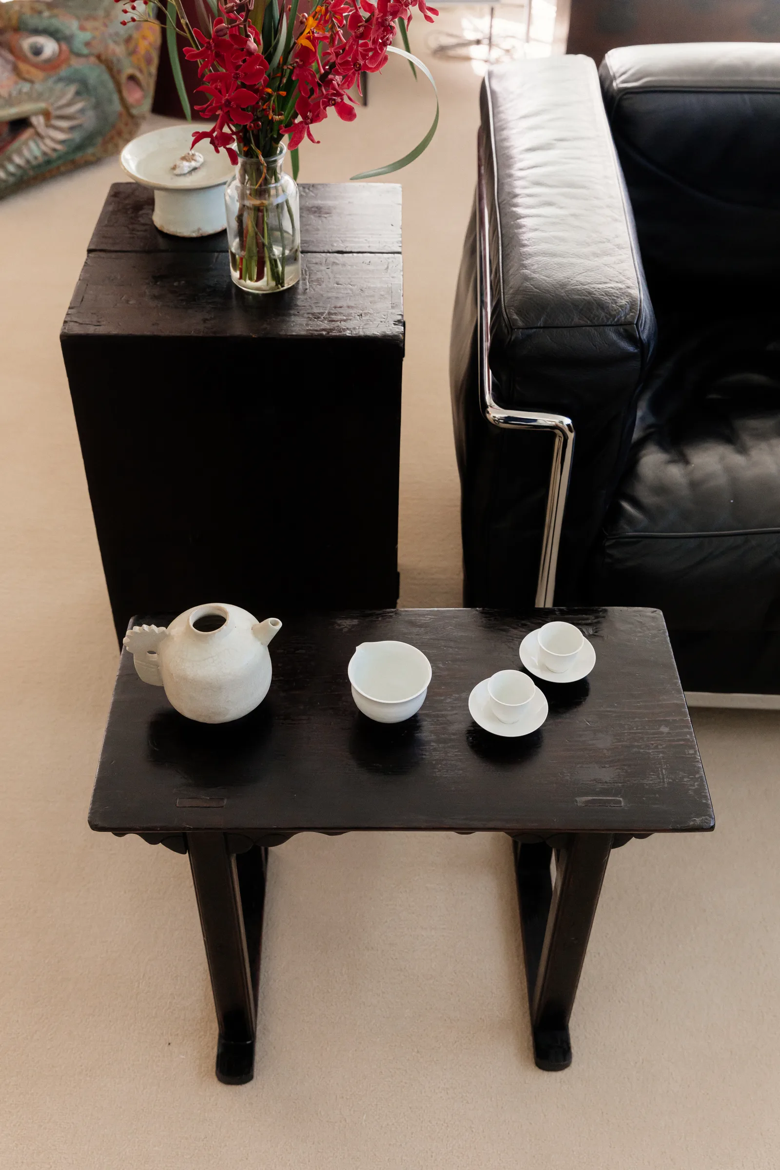 Tea set on a black soban beside a leather sofa