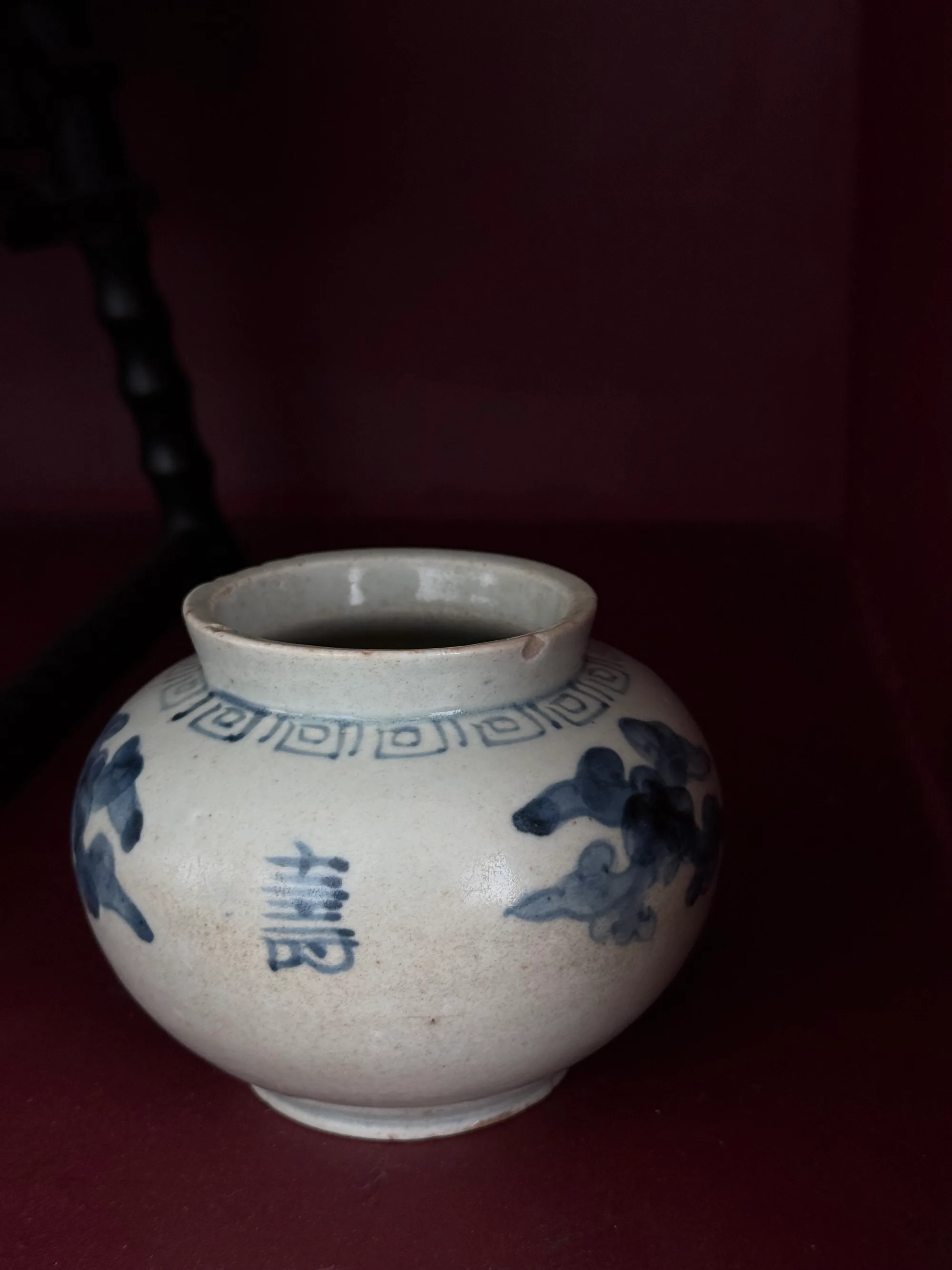 The blue-and-white su jar inside a red-lacquered cabinet
